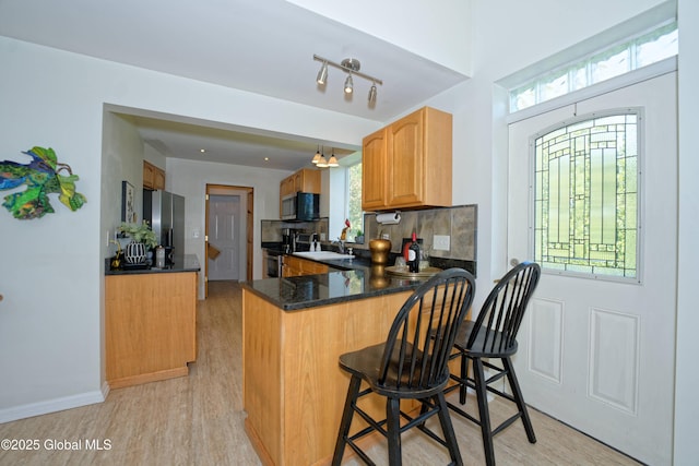 107 Wilderness Way, Stephentown, NY 12169 - kitchen featuring stainless steel appliances, light wood finished floors, a peninsula, dark countertops, and a kitchen breakfast bar