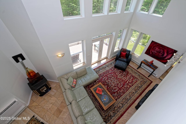 107 Wilderness Way, Stephentown, NY 12169 - living room featuring a wood stove, a towering ceiling, a baseboard radiator, and french doors