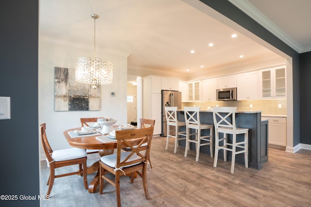 dining room with ornamental molding, recessed lighting, a notable chandelier, and wood finished floors