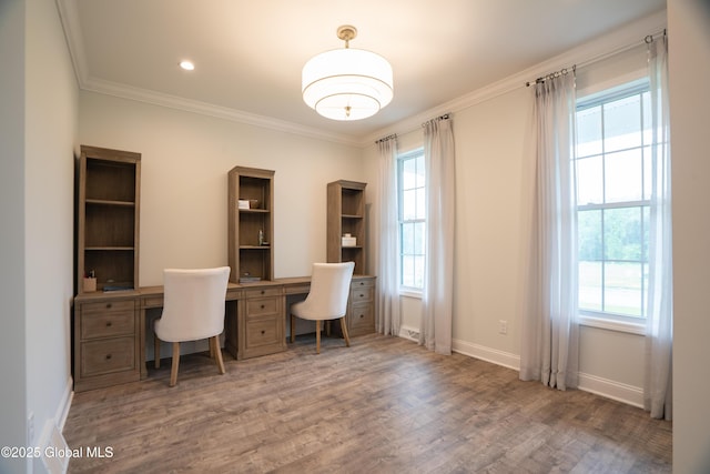 home office with wood finished floors, crown molding, baseboards, and built in study area