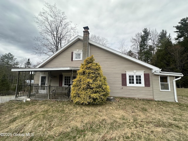 view of side of home with a lawn and a chimney