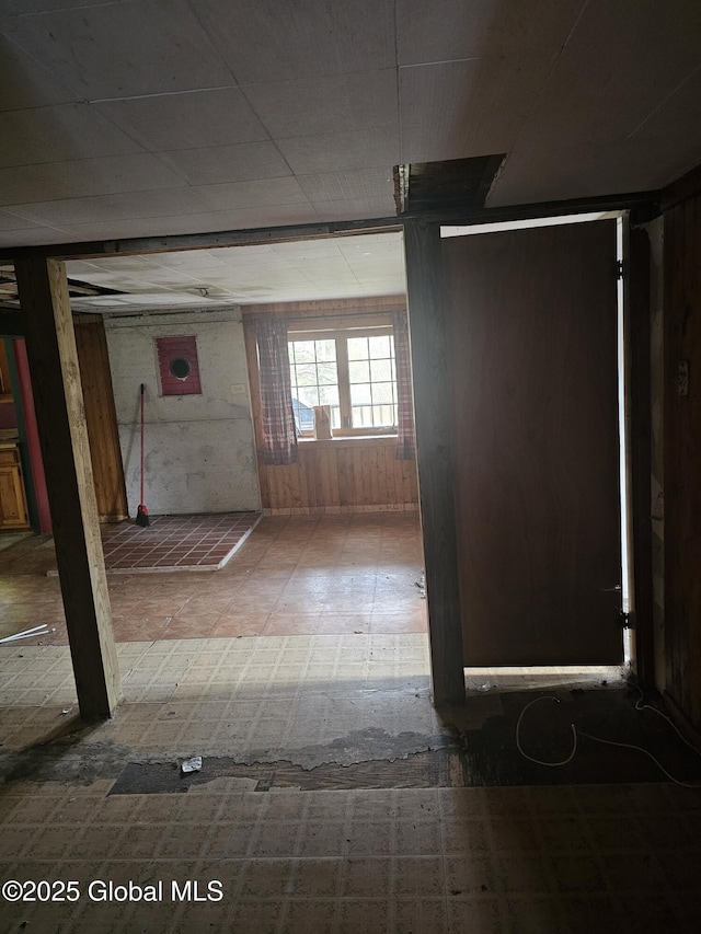below grade area featuring tile patterned floors and wood walls