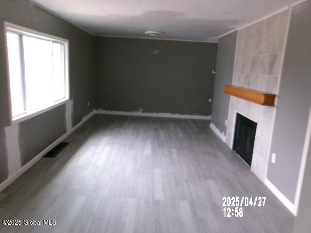 unfurnished living room featuring baseboards, wood finished floors, a fireplace, and visible vents