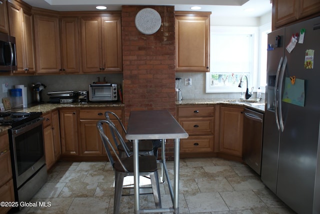 kitchen featuring a toaster, stone tile flooring, stainless steel appliances, and a sink