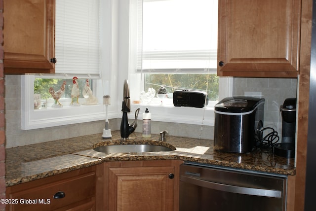 kitchen featuring dark stone countertops, stainless steel dishwasher, backsplash, and a sink