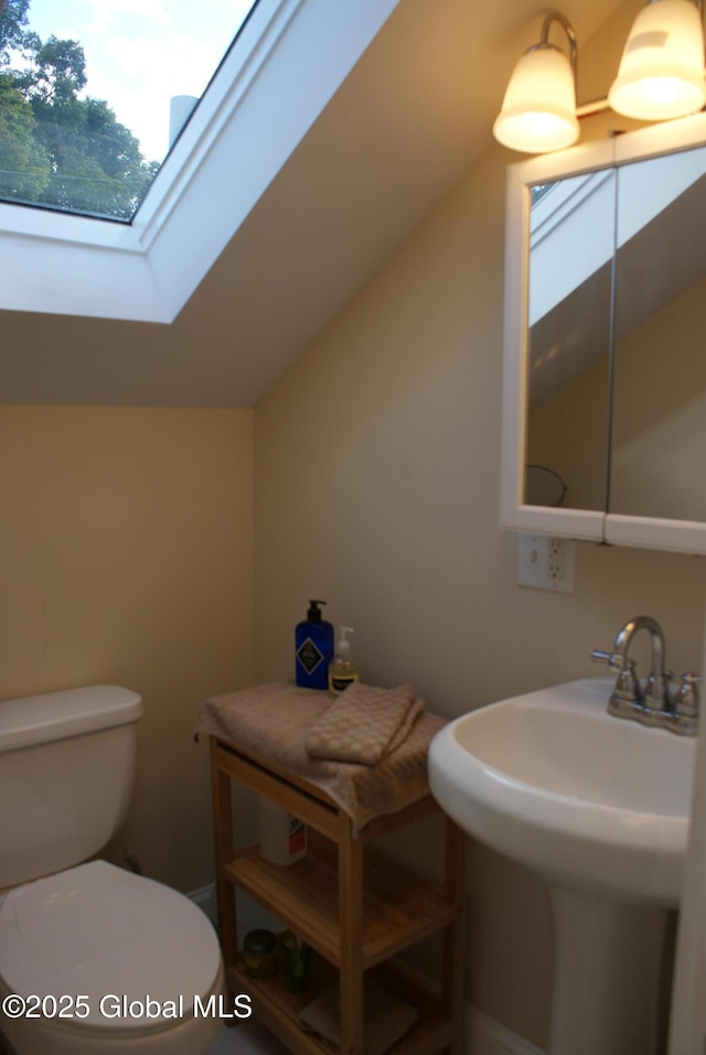 half bath with a skylight, toilet, and a sink