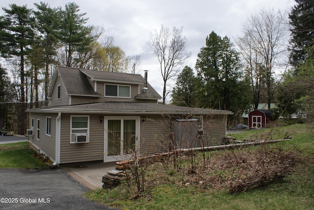 view of front of house featuring roof with shingles, a shed, and an outbuilding