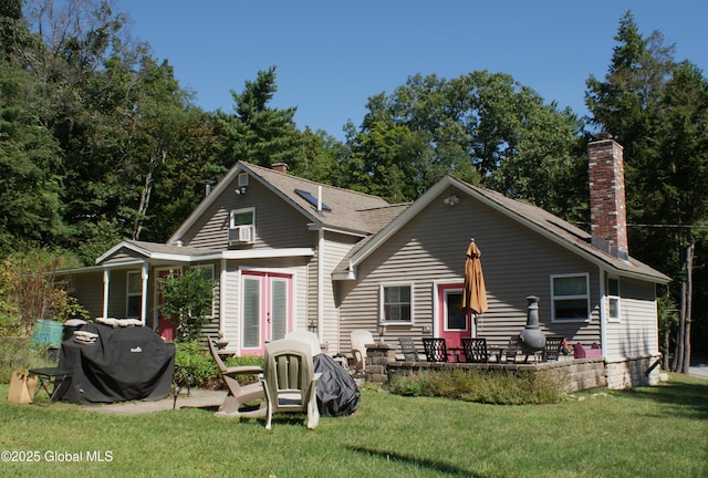 back of property featuring a chimney, french doors, a yard, and a patio area