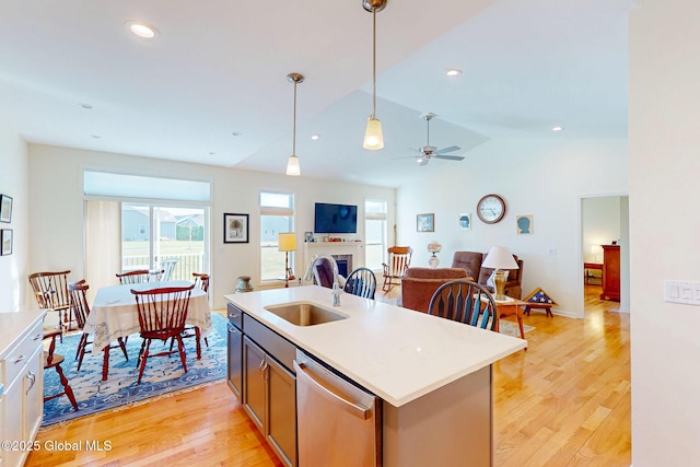 kitchen with ceiling fan, a sink, dishwasher, light wood-type flooring, and pendant lighting