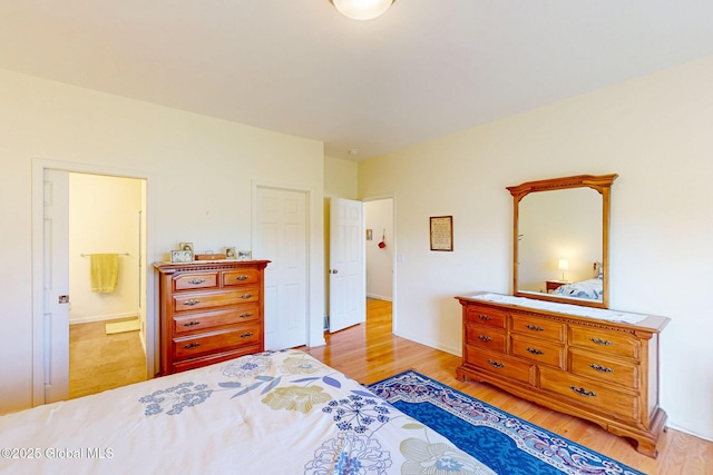 bedroom featuring connected bathroom and light wood-style flooring