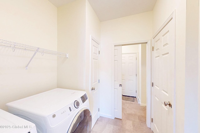 clothes washing area with washer / dryer, baseboards, and laundry area