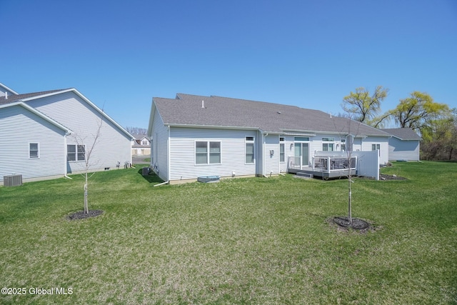 back of property with a yard, cooling unit, a wooden deck, and a shingled roof