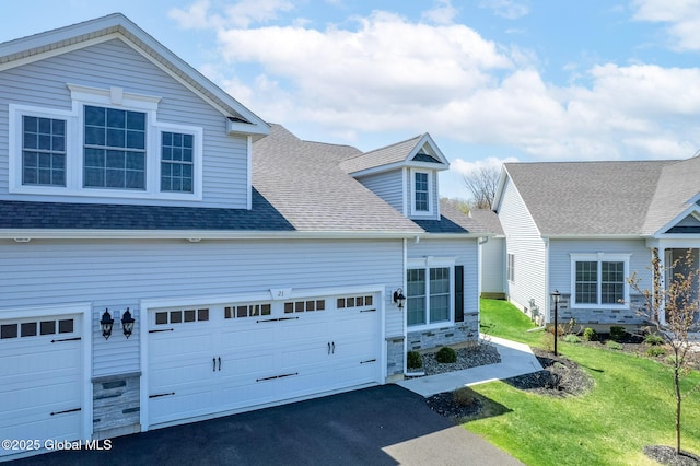 view of front of house with a garage, a front lawn, aphalt driveway, stone siding, and roof with shingles