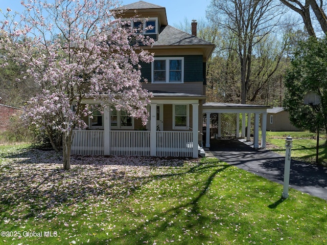 view of front of property with a porch, a chimney, a front lawn, driveway, and an attached carport