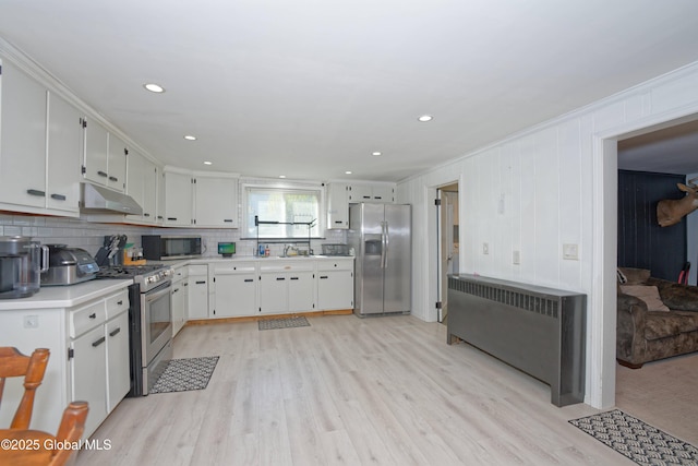 kitchen with light wood-type flooring, light countertops, under cabinet range hood, radiator heating unit, and stainless steel appliances