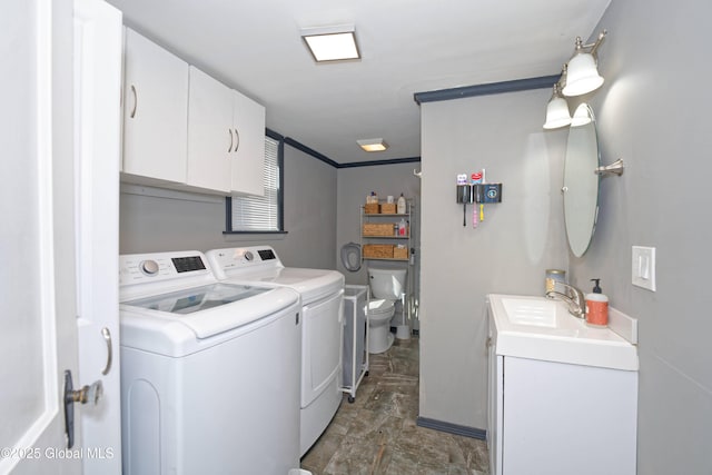 laundry area with laundry area, stone finish flooring, washing machine and clothes dryer, a sink, and baseboards