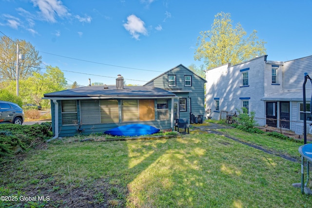 rear view of property with a yard, fence, and a chimney