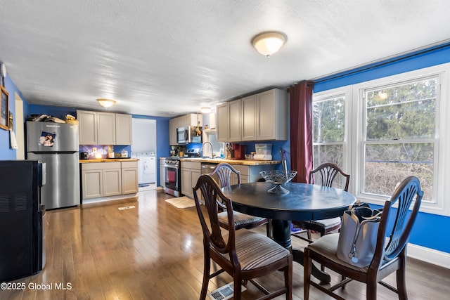 dining room with a textured ceiling, hardwood / wood-style floors, and washer / clothes dryer