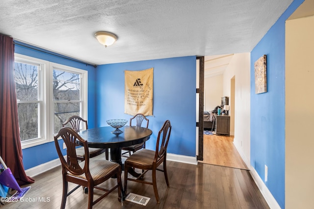 dining space featuring a textured ceiling, wood finished floors, and baseboards