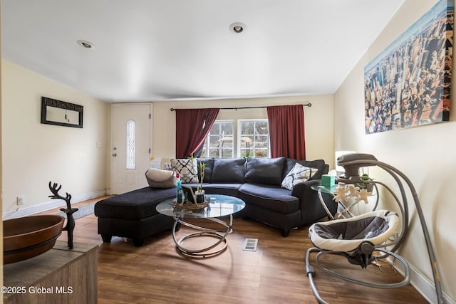 living area with wood finished floors, visible vents, and baseboards