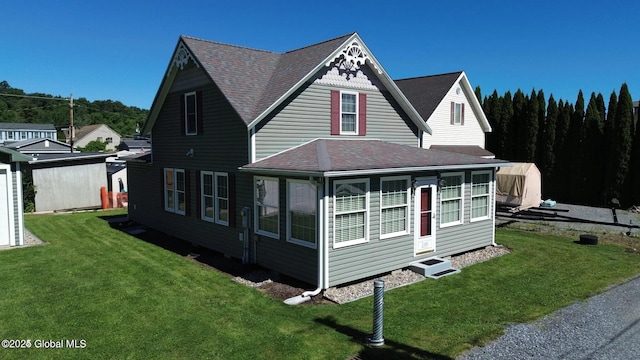 view of front of property with roof with shingles and a front yard
