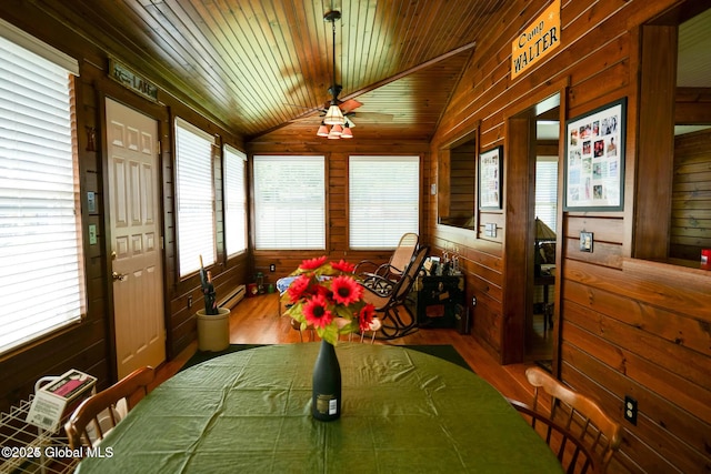 sunroom / solarium featuring wooden walls, a wealth of natural light, lofted ceiling, and wood finished floors