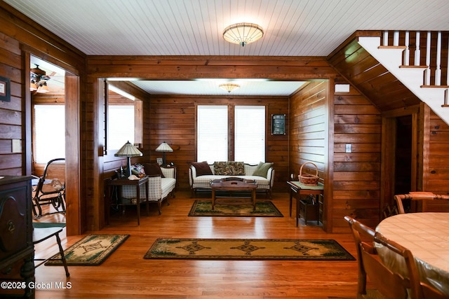 living room with wood walls, wood finished floors, and stairs