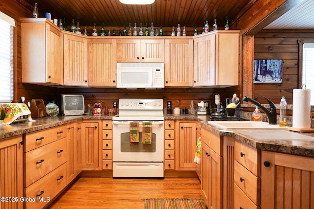 kitchen with light brown cabinets, white appliances, a healthy amount of sunlight, light wood-type flooring, and a sink