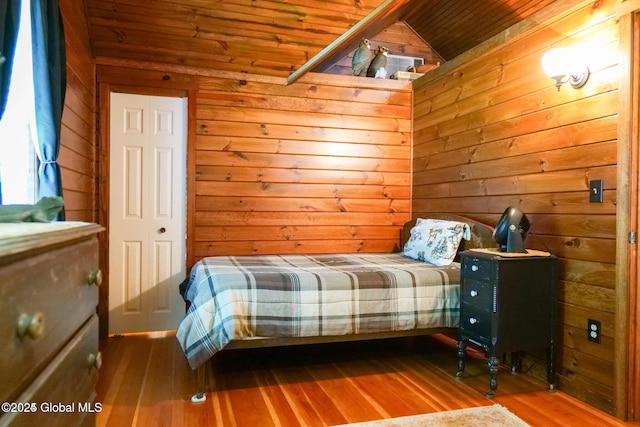 bedroom with wood walls, wood ceiling, vaulted ceiling, and wood finished floors