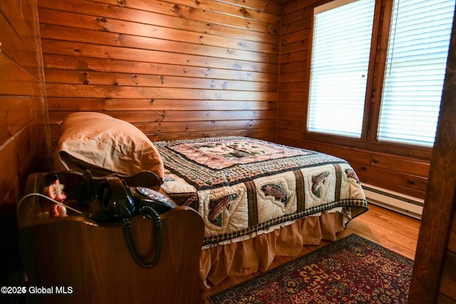 bedroom featuring a baseboard radiator, wood finished floors, and wooden walls