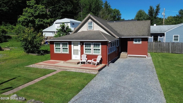 view of front of property featuring a shingled roof, a front lawn, and fence