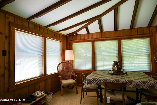sunroom with carpet floors, wood walls, and vaulted ceiling with beams