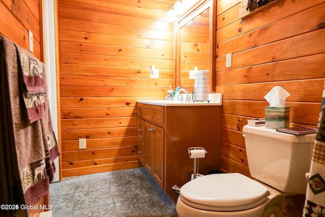 half bath with vanity, tile patterned floors, wooden walls, and toilet