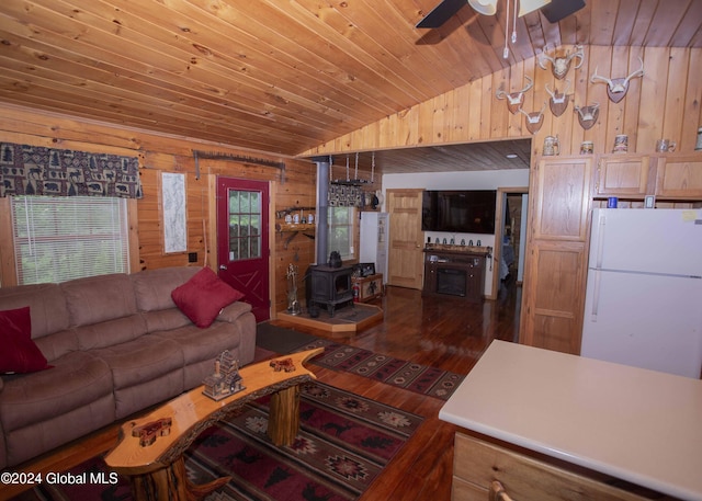 living area with a wood stove, wood walls, ceiling fan, wooden ceiling, and vaulted ceiling