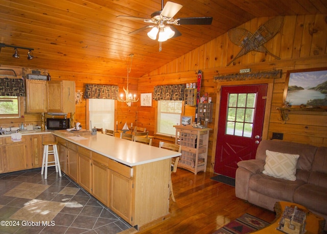 kitchen featuring wood walls, a peninsula, and vaulted ceiling