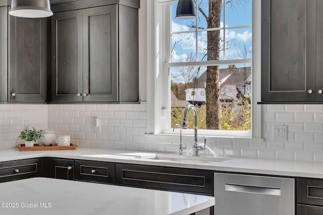 kitchen featuring light stone counters, a sink, decorative backsplash, and dishwasher
