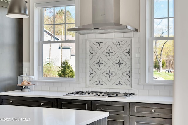 kitchen featuring tasteful backsplash, light countertops, and wall chimney exhaust hood