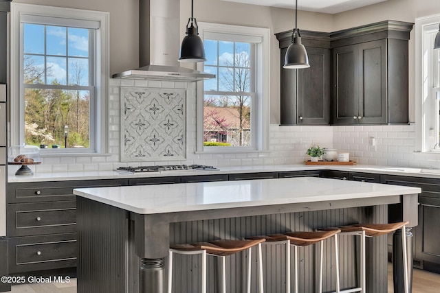 kitchen featuring extractor fan, stainless steel gas stovetop, backsplash, a kitchen bar, and a kitchen island