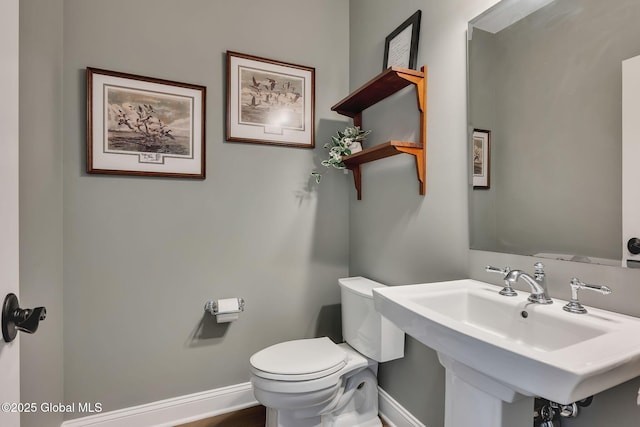 bathroom with toilet, baseboards, and a sink