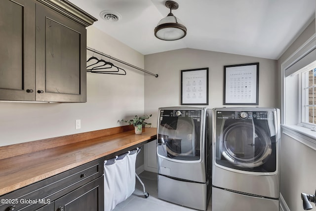 washroom with washing machine and clothes dryer, cabinet space, light tile patterned floors, and visible vents