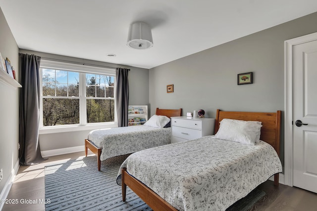 bedroom with baseboards and dark wood-type flooring