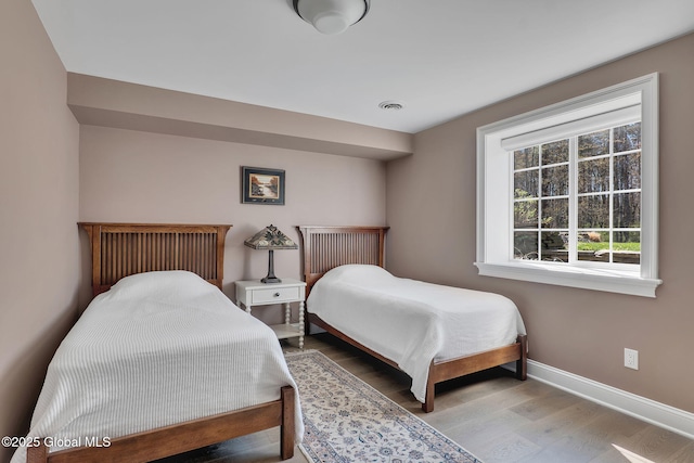bedroom featuring baseboards, visible vents, and wood finished floors