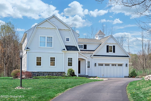 shingle-style home featuring a front lawn, driveway, a shingled roof, and a garage