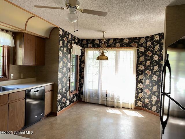 kitchen featuring freestanding refrigerator, baseboards, wallpapered walls, a textured ceiling, and dishwasher
