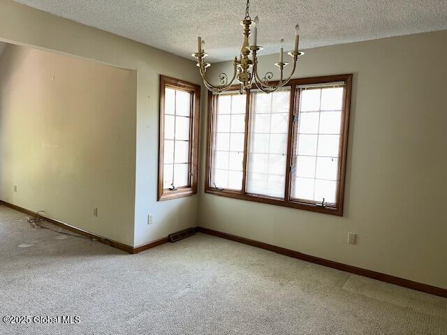unfurnished room featuring visible vents, carpet, and a chandelier