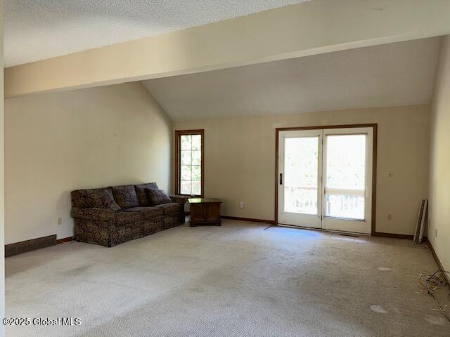 living room featuring baseboards, vaulted ceiling with beams, and light carpet