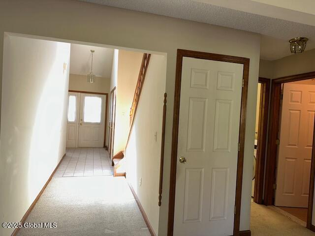 hallway with light colored carpet and baseboards