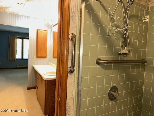 bathroom with vanity, a baseboard radiator, and a tile shower