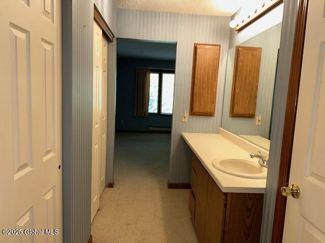 bathroom featuring vanity, a textured ceiling, baseboards, and wallpapered walls