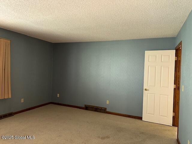 carpeted empty room with a textured ceiling and visible vents